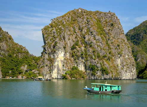 Green fishing boat in front of limestone rock in Vietnam's Ha Long Bay