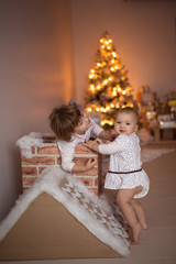 funny little sisters (sibling) playing in a cardboard chimney,