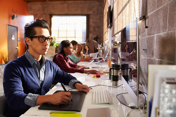 Designers Working At Desks In Modern Office