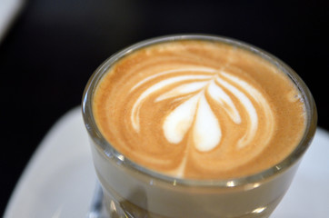 A cup of coffee with heart pattern in a white cup..