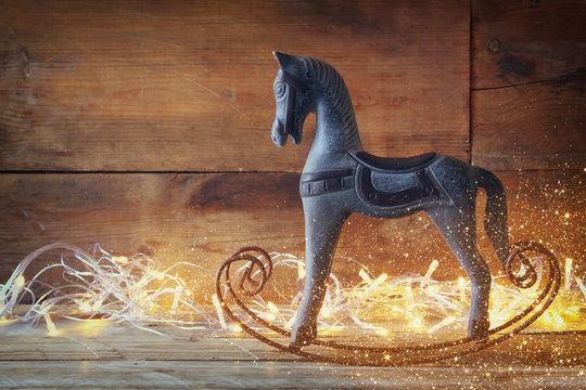 image of rocking horse and magic christmas lights on wooden table

