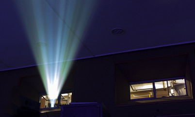 blue and yellow projector ray in dark cinema showing room © maxcam