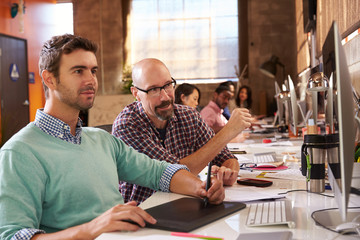 Designers Working Together At Desks In Modern Office