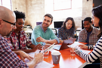 Group Of Designers Having Meeting Around Table In Office