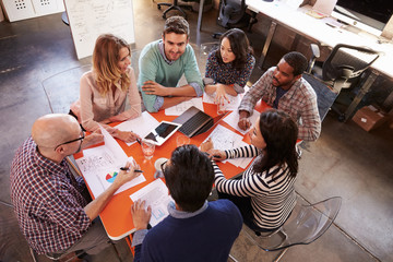 Overhead View Of Designers Having Meeting Around Table