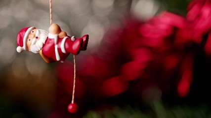 Un père noël de décoration grimpe à la corde au sapin