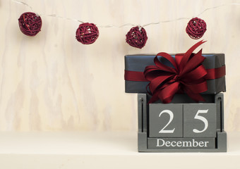 Christmas Vintage Wood Calendar with a festive present gift and decorative small balls isolated on wooden background. 