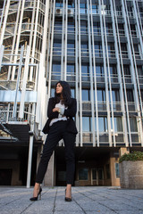 Businesswoman. Pretty Latina business woman posing in a photo session in the sun. She wears sunglasses and elegant black suit with white shirt. 