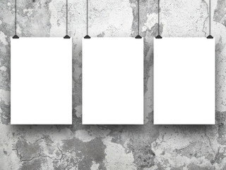Three hanged paper sheet frames with clips on grey cracked and scratched concrete wall background