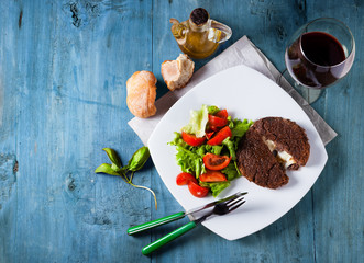 Burger cutlet stuffed with cheese inside of legumes with vegetab
