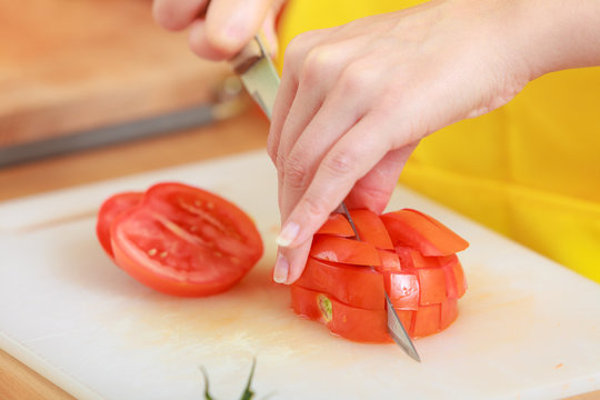 Woman preparing vegetables salad slicing tomato