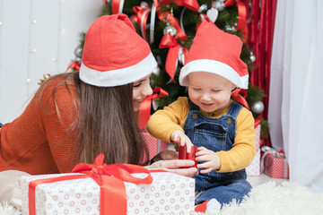 Obraz na płótnie Canvas Happy mother giving to baby Christmas gift