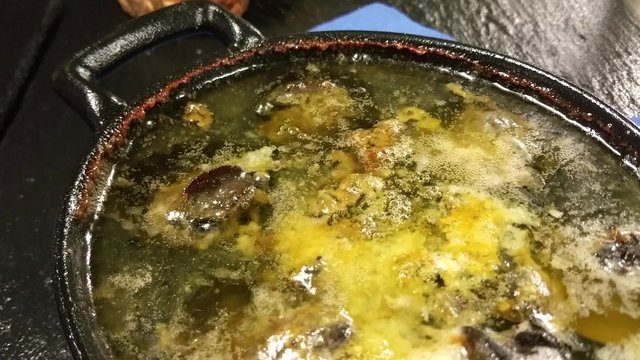 Bubbling, cooked escargot snail pan, at a restaurant kitchen