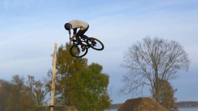 Extreme mountain biker does tricks over dirt jumps-steady follow shot