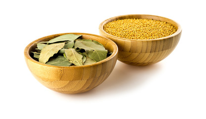 Culinary bay leaves and mustard seeds in wooden bowls