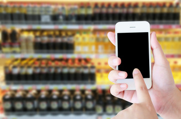 Female hand holding mobile smart phone on Supermarket blur backg