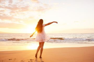 Fototapeta na wymiar Happy Carefree Woman Dancing on the Beach at Sunset