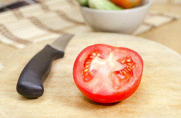 tomato cut in half on wooden cutting boards with knife