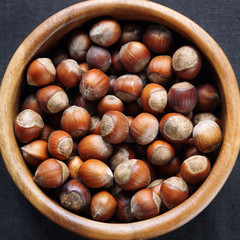 Hazelnuts in a wooden bowl on a dark background