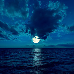 full moon in dramatic sky over water in night