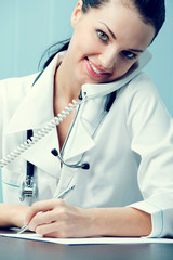 Portrait of happy successful doctor on phone at office