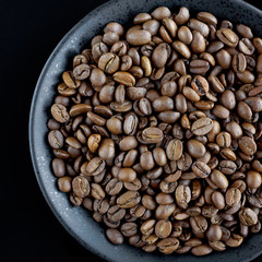 Coffee beans on a black plate on a black background