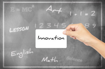 Hand holding card with word of "Innovation" against chalkboard b