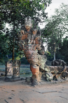 Stone carved devil image holding naga or dragon tail