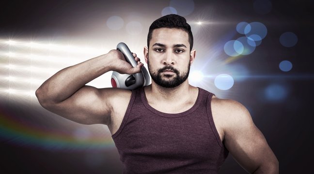 Composite image of muscular serious man holding a kettlebell