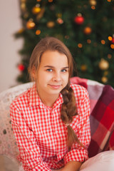 Teen girl with pigtails in a red plaid shirt in Christmas decorations