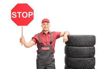 Young male mechanic holding a stop sign