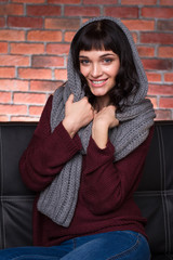 Cheerful young woman in knitted gray scarf, sweater and jeans