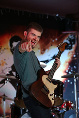 Obraz premium Young man playing on electric guitar at pub