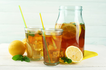 Iced tea with lemon on light wooden background