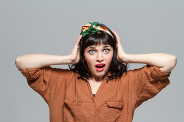 Shocked dazed woman with opened mouth holding head by hands