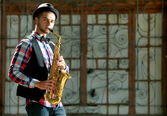 Man with saxophone outside near the brick wall