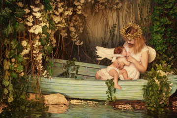 Mother breastfeeding her Baby Angel with wings on fairy boat in garden. Christmas abstract concept,...