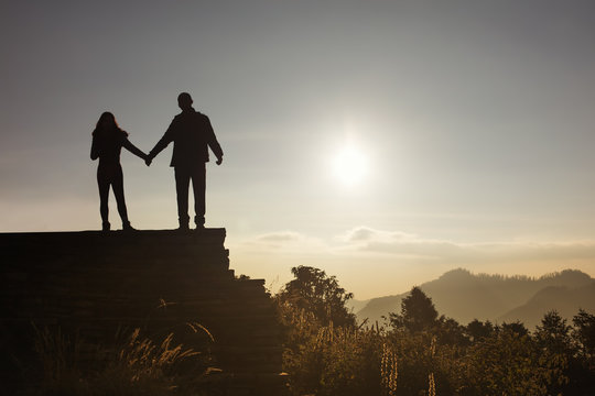 Love couple silhouette looking sunrise in mountains