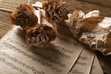 Naklejka premium Beautiful paper-made roses on musical notes page background