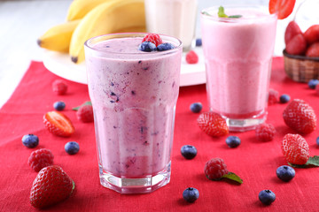 Milkshakes with berries at red textile on light background