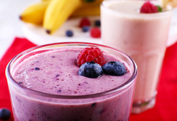 Milkshakes with berries at red textile on light background, close-up