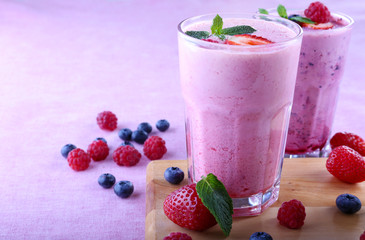 Milkshakes at cutting board with berries on light background