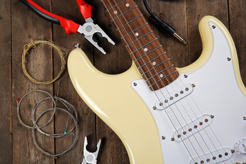 Fototapeta premium Electric guitar with pliers and cords on wooden background