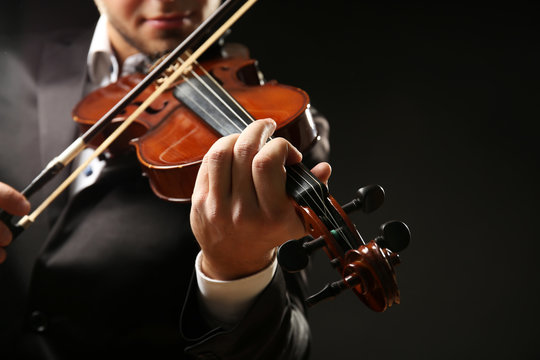 Musician play violin on black background, close up