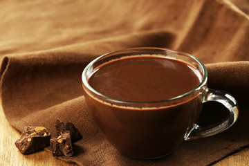 Cup of cacao with chocolate and napkin on wooden table