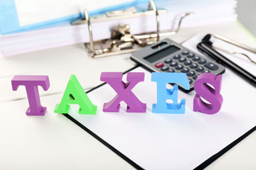 Alphabet TAXES with calculator and papers on table