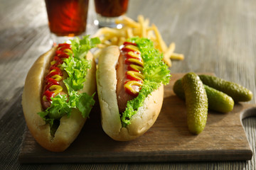 Delicious hot-dogs with pickled cucumbers on wooden chopping board
