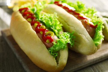 Delicious hot-dogs with pickled cucumbers on wooden chopping board, close up