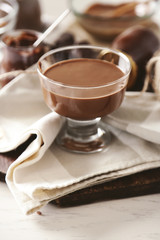 Melted chocolate on glass bowl, on wooden background