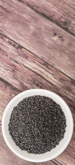 Black sesame seed in white bowl over wooden background